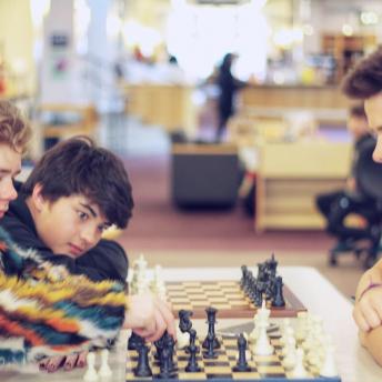Three teenage boys playing chess