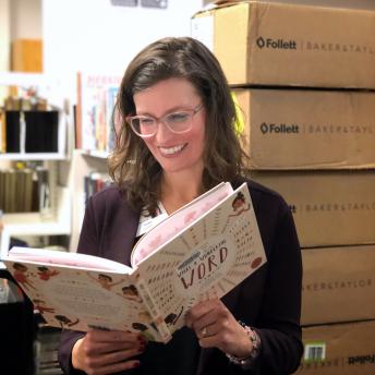 Library staff member holds book in tech services department