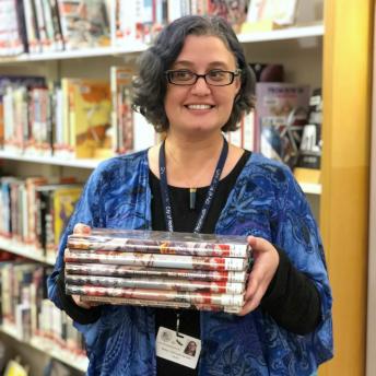 Library staff member with stack of graphic novels