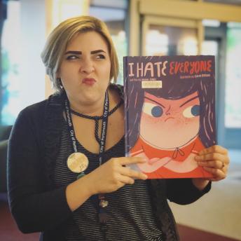 Staff member holds book that says "I Hate Everyone"