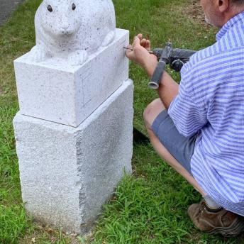Thomas Berger, sculptor, is drilling holes for plaque installation.