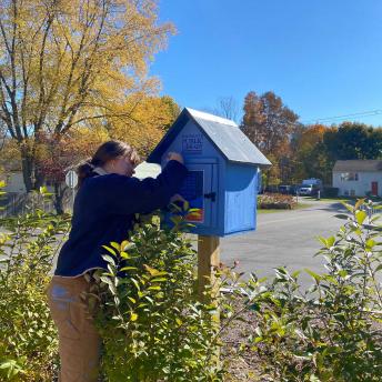 Loreley works on installing the Little Free Library at Senior Center