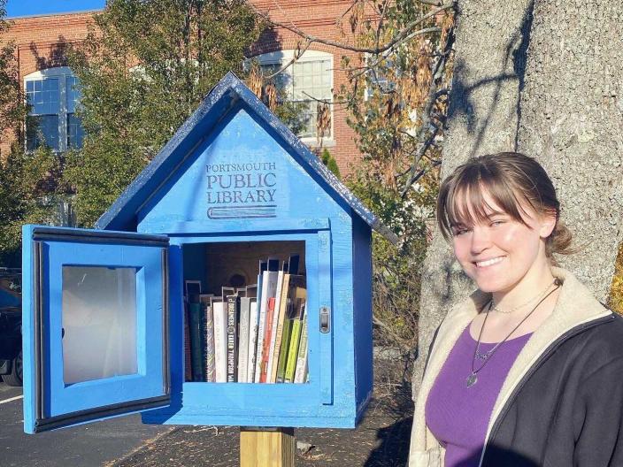 Loreley stands beside a fully stocked Little Free Library